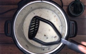 potato masher over instant pot with rice pudding