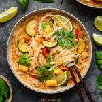 Thai red curry soup with noodles, chicken and vegetables, garnished with basil