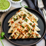four Indian-style waffle halves on a plate, made with cilantro and tomato
