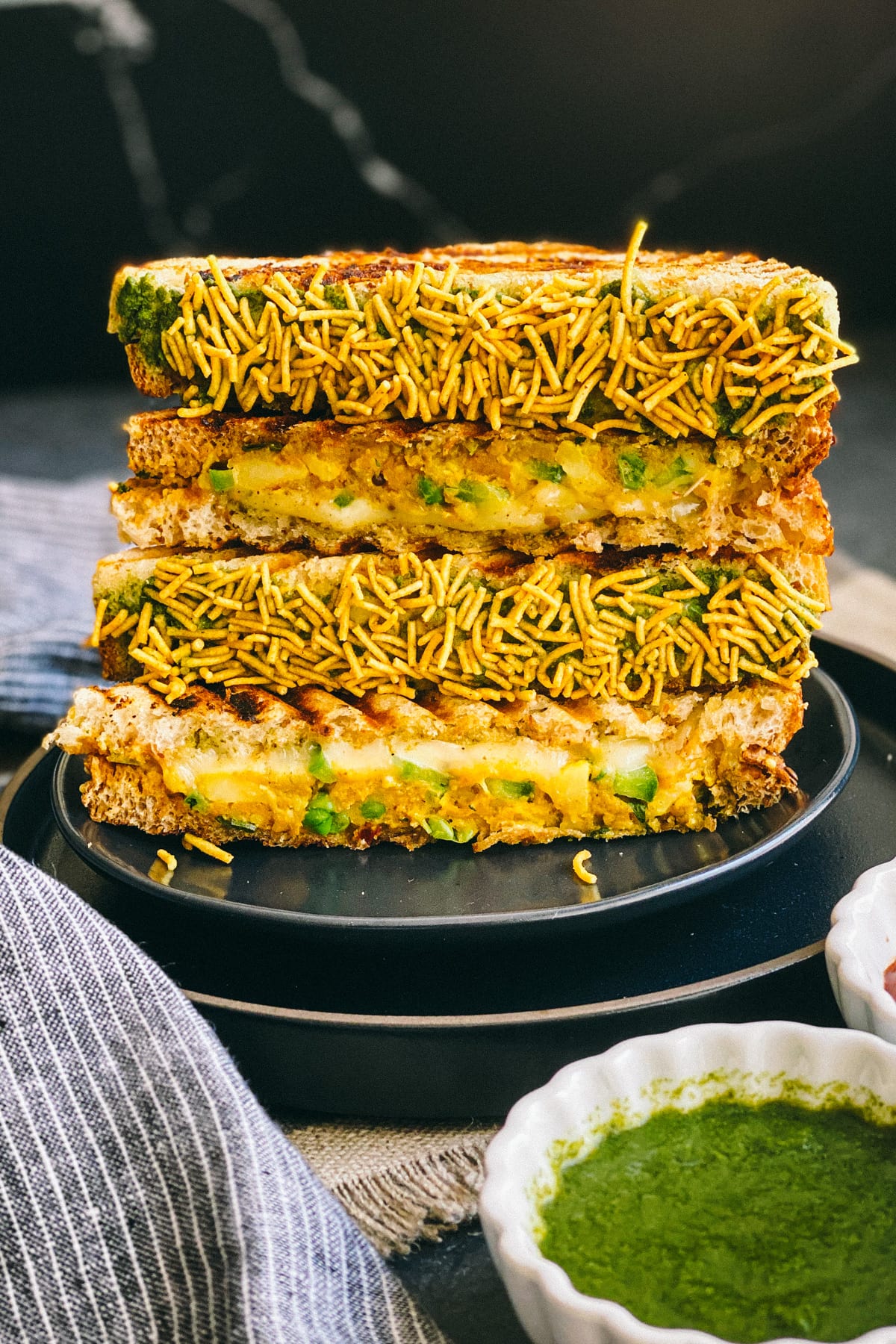 stack of bombay cheese toastie coated in namkeen on black plate