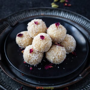 Plate of stacked coconut ladoo, topped with dried rose leaf
