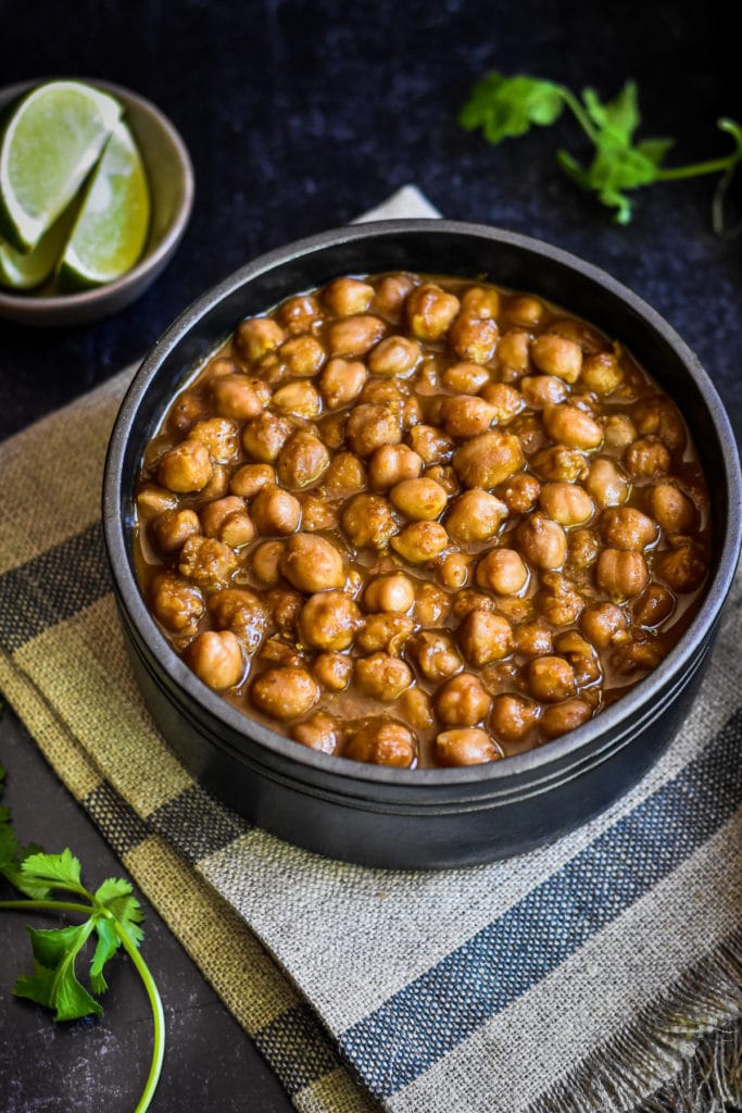 easy punjabi chole recipe in black bowl with lime wedges