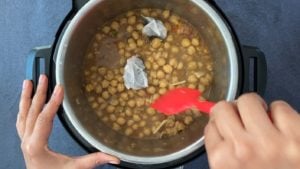 stirring chickpeas and tea bags in instant pot with red spatula