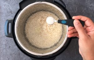 Adding water and salt to the pot with rice