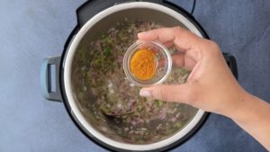 turmeric in small glass bowl over instant pot with aromatics