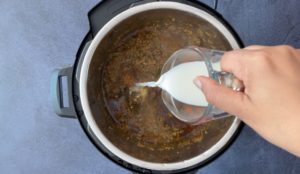 pouring milk into instant pot with lamb curry