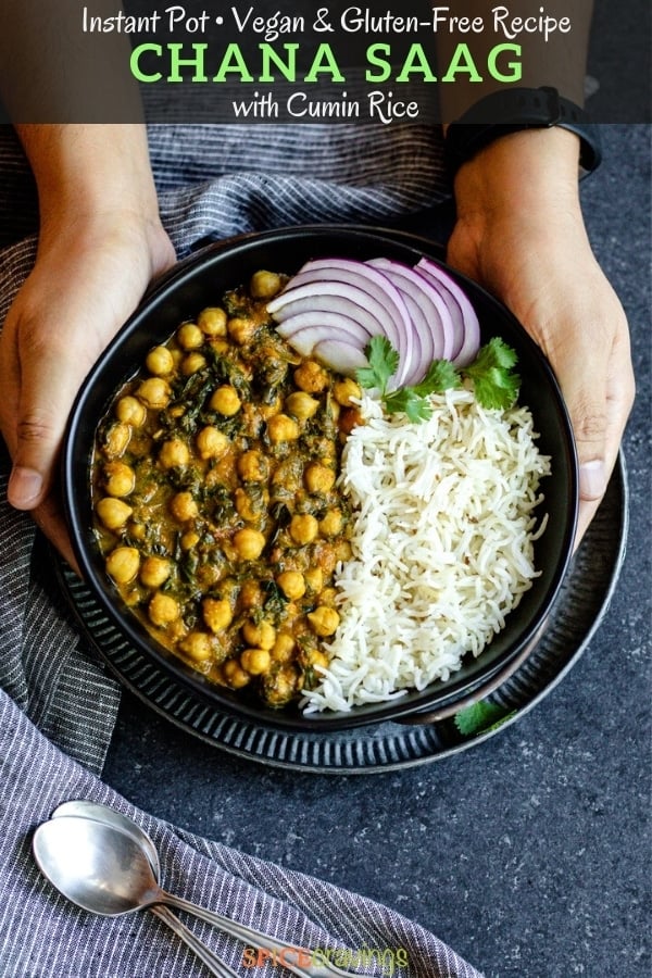 two hands holding chana saag and cumin rice with sliced red onions in black bowl