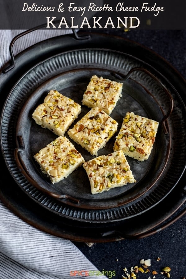 kalakand squares topped with pistachios and almonds on black plate