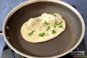 butter and nigella seed topped flatbread in nonstick skillet