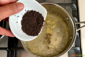 Adding tea leaves to the pot of water