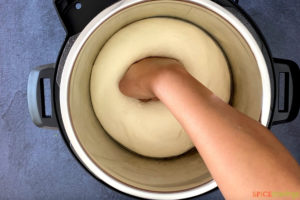 hand punching down dough in instant pot