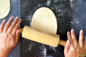 two hands rolling out Indian flabread