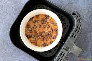 A white bowl of uncooked bread pudding inside the basket of an air fryer