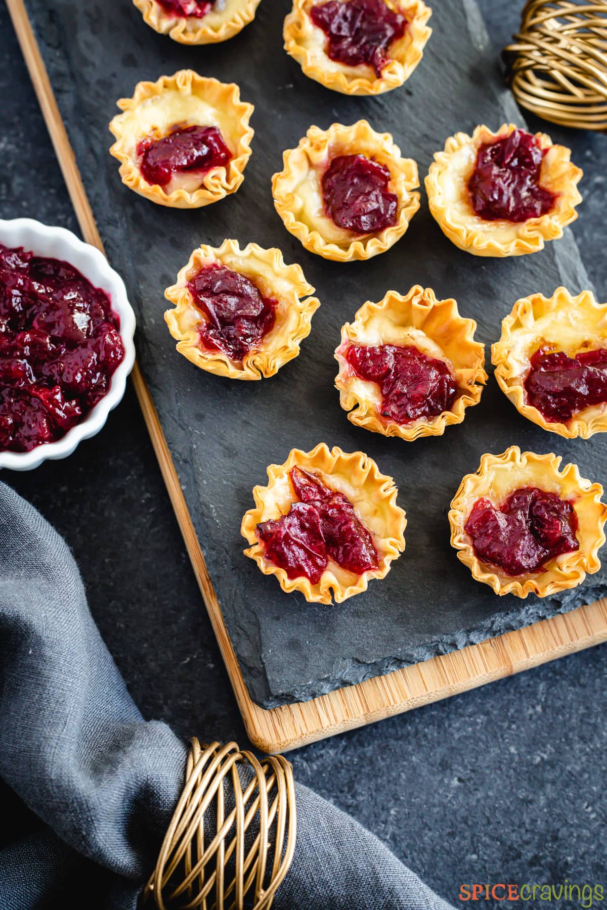 Cranberry brie bites on a tray next to a bowl of cranberry sauce