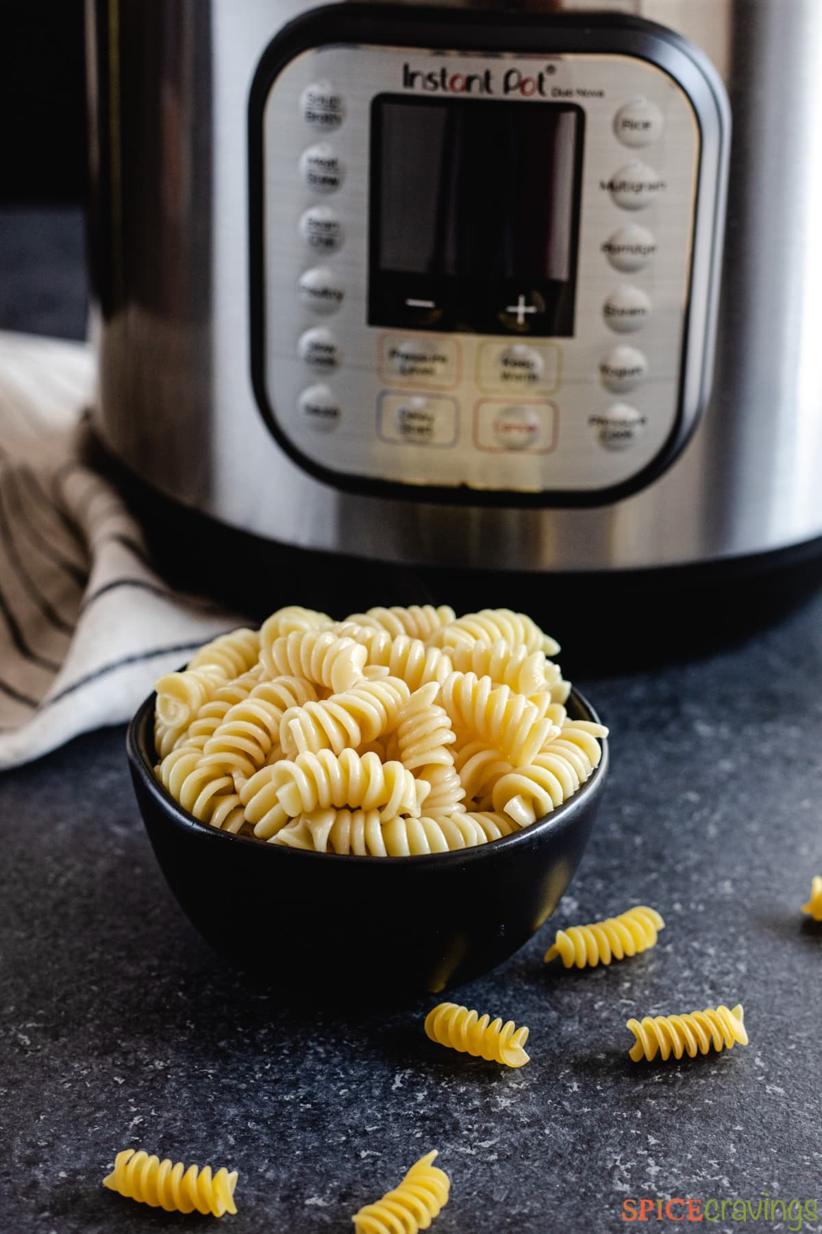 A bowl of rotini pasta next to an Instant Pot