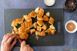 Hands cutting pieces of croissants on a cutting board
