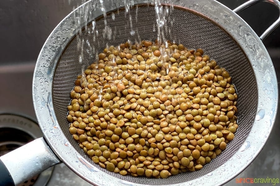 Rinsing lentils in a strainer over the sink