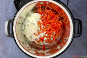 Red bell peppers and onions in a pressure cooker