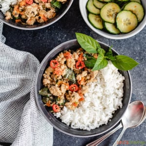 A bowl of Thai basil chicken with a serving of rice in abowl