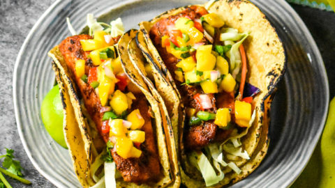 Two grilled fish tacos topped with mango salsa