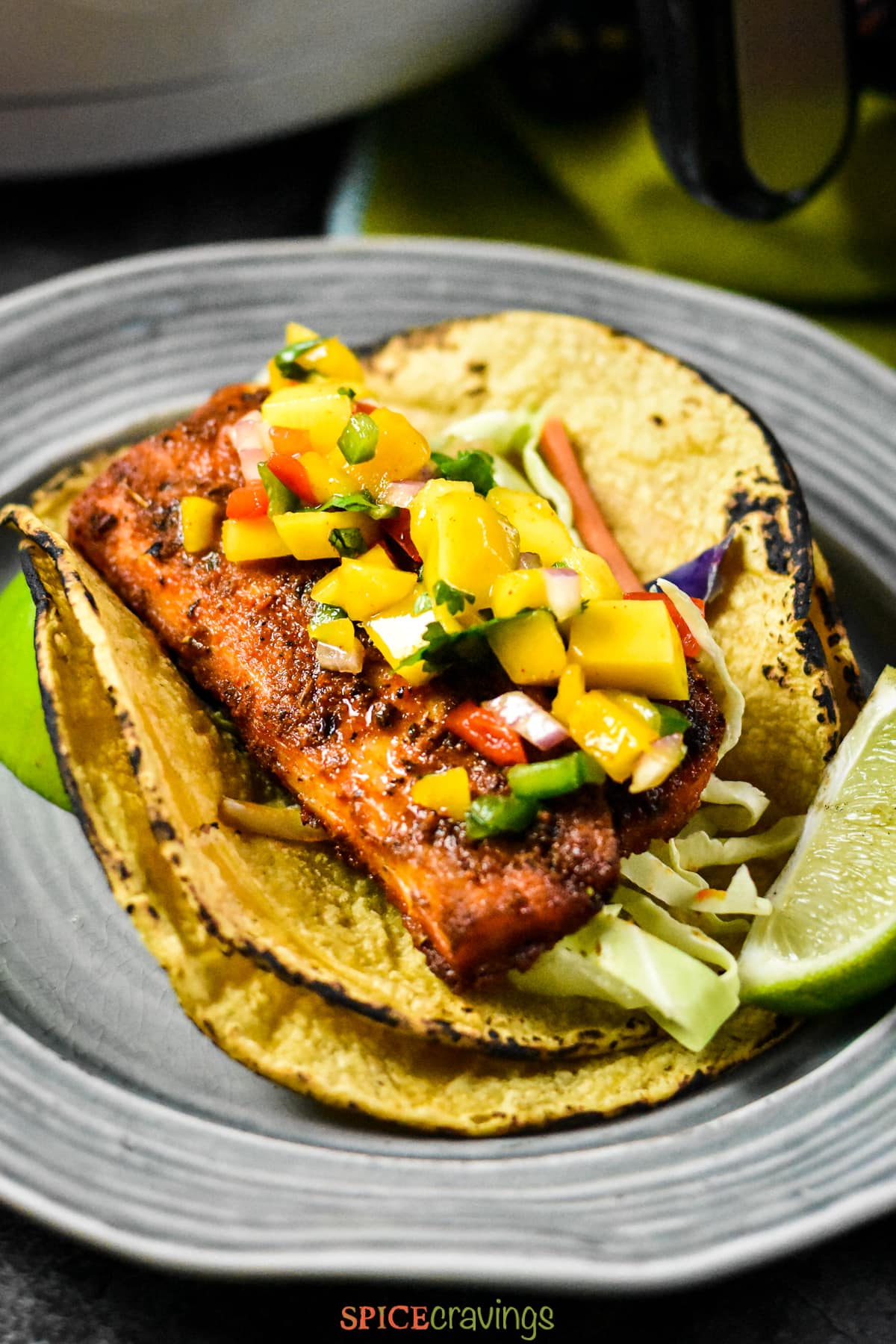 Spicy grilled fish on corn tortilla topped with mango salsa