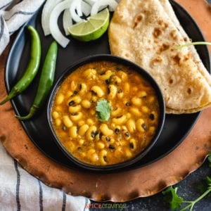 Black eyed peas curry in a black bowl with roti