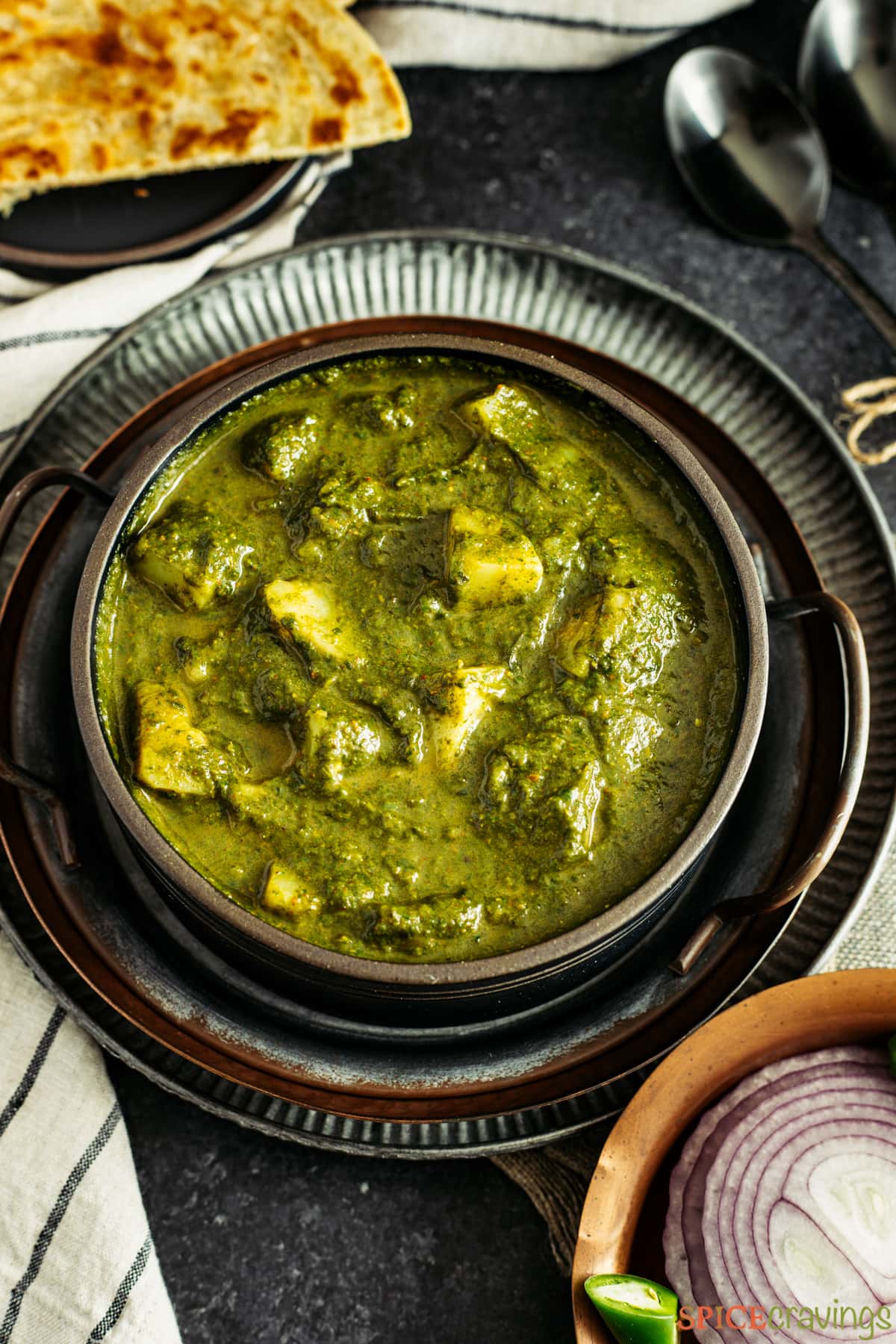 Spinach and potato curry in a black stone pot