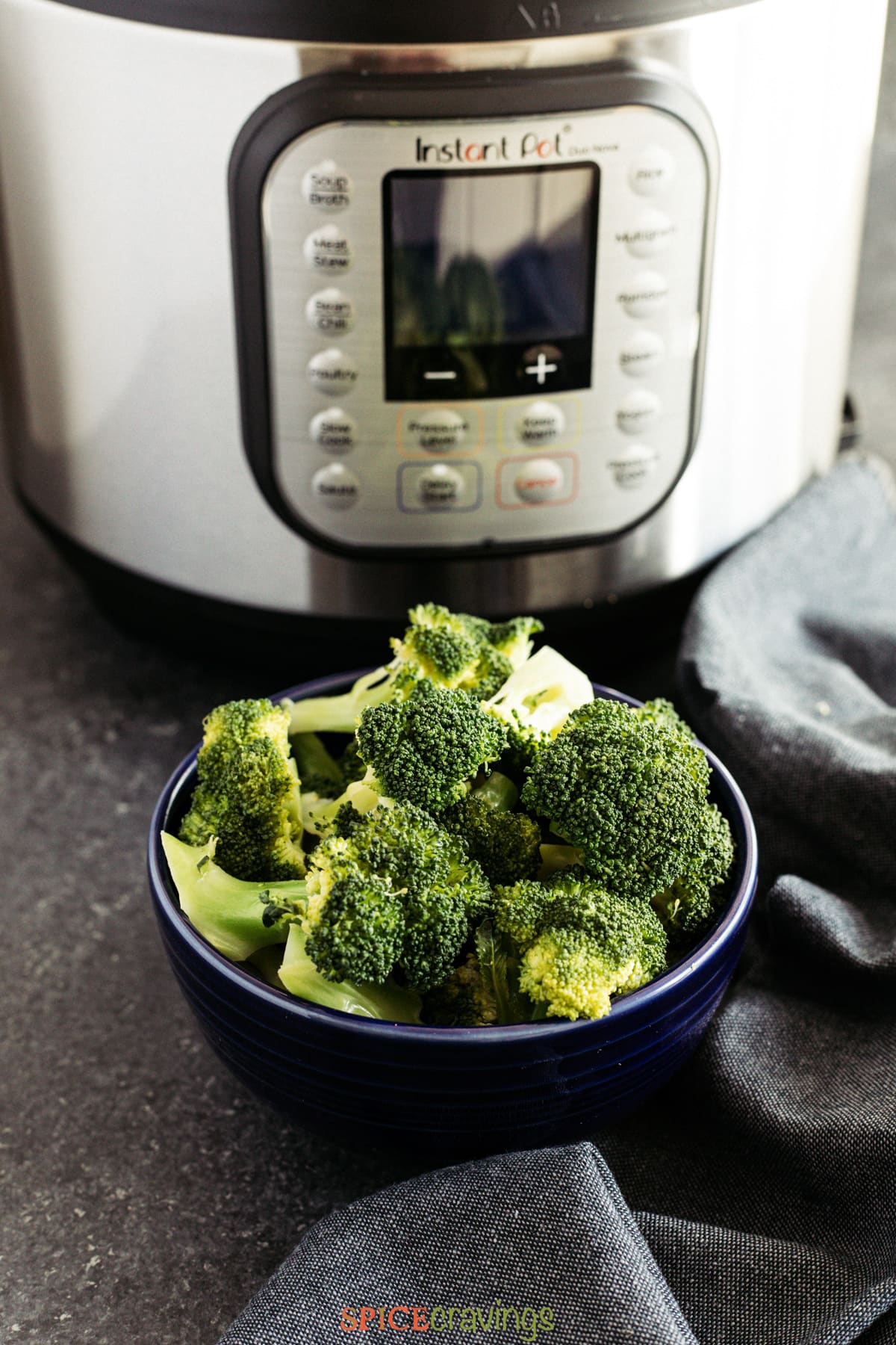 A bowl of steamed broccoli in front of an Instant Pot