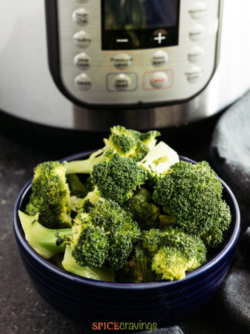 A bowl of steamed broccoli in front of an Instant Pot