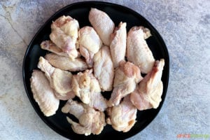 Uncooked chicken wings on a black plate