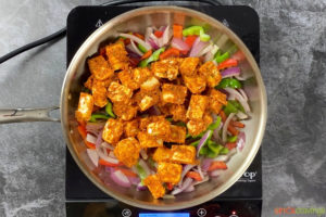 Paneer and vegetables cooking in a pan