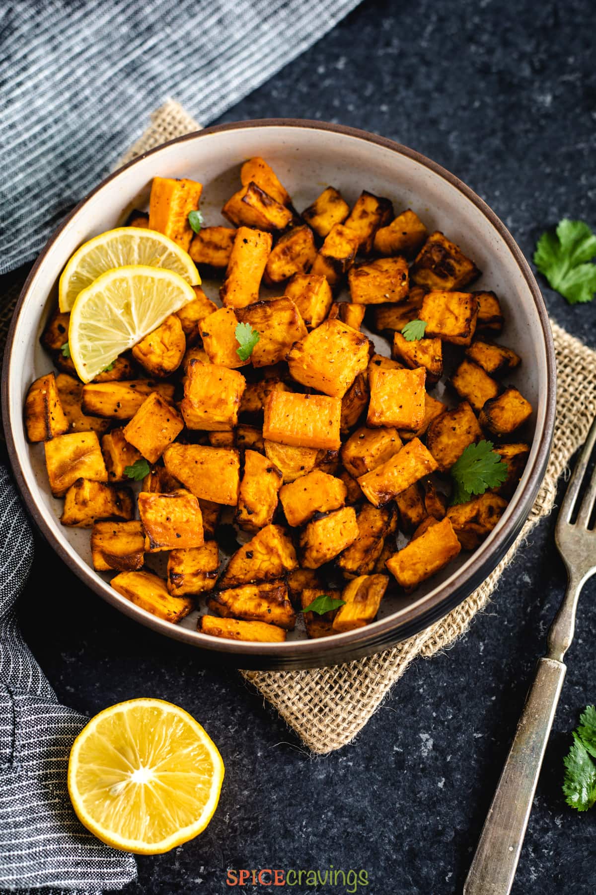 Cubes of roasted sweet potatoes in a bowl with lemon wedges