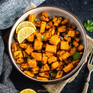 Cubes of roasted air fryer sweet potatoes in a bowl with lemon wedges