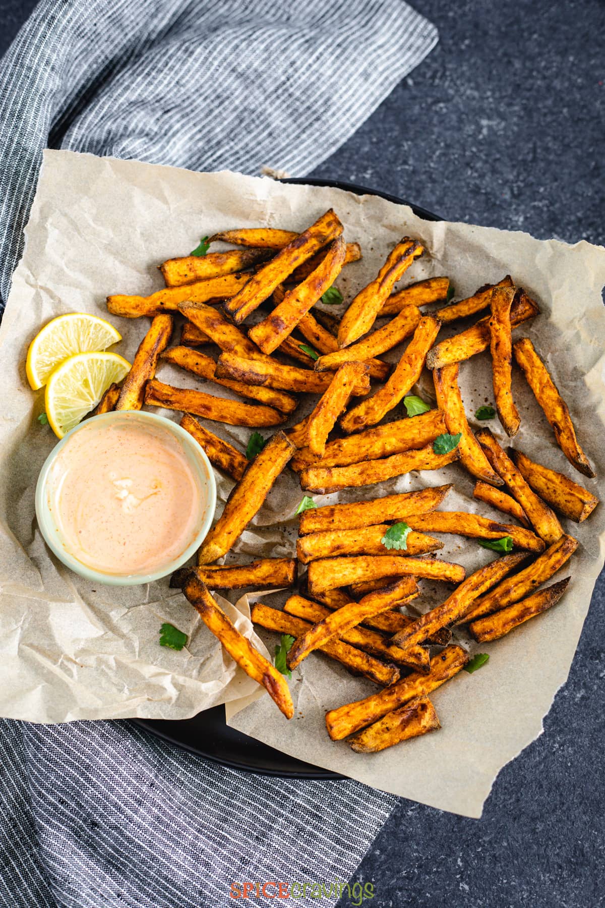 Sweet potato fries on a piece of parchment paper with dip