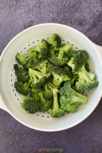 Broccoli florets in a white strainer