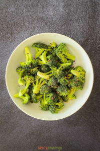 Broccoli florets with seasoning in a white bowl