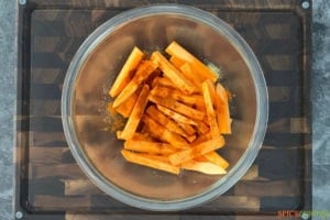 Slices of yams in a bowl being seasoned