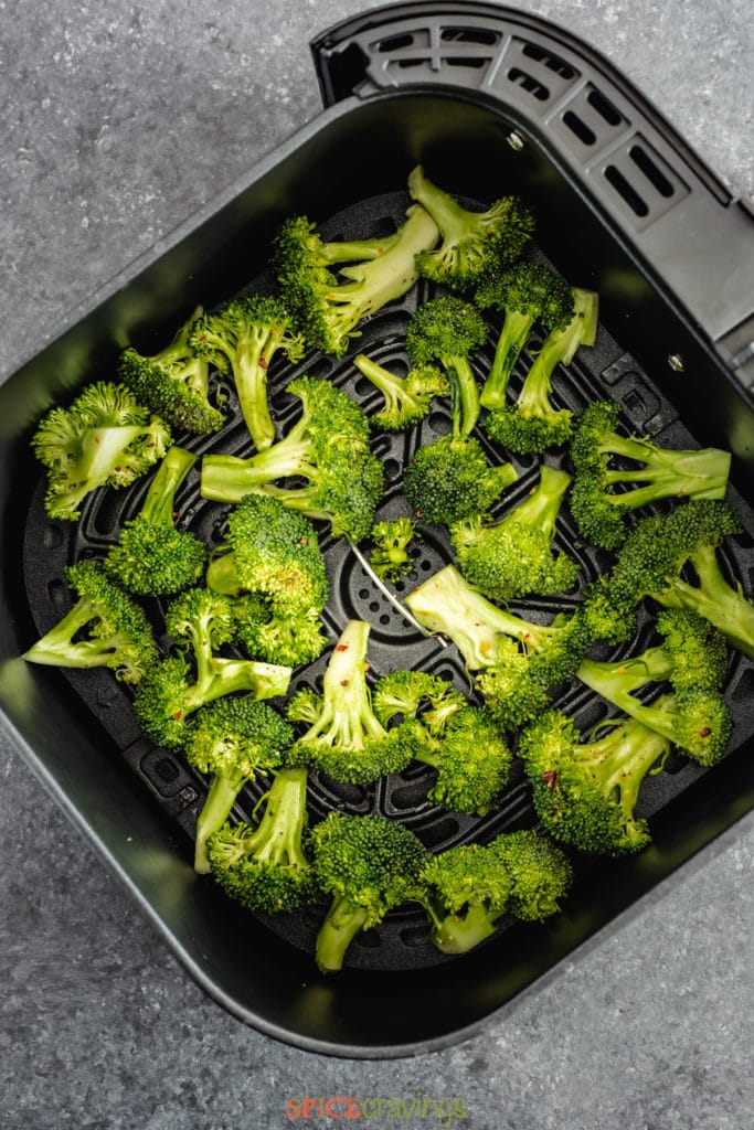 Green broccoli florets in air fryer basket