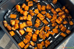 Cubes of roasted sweet potatoes in an air fryer basket
