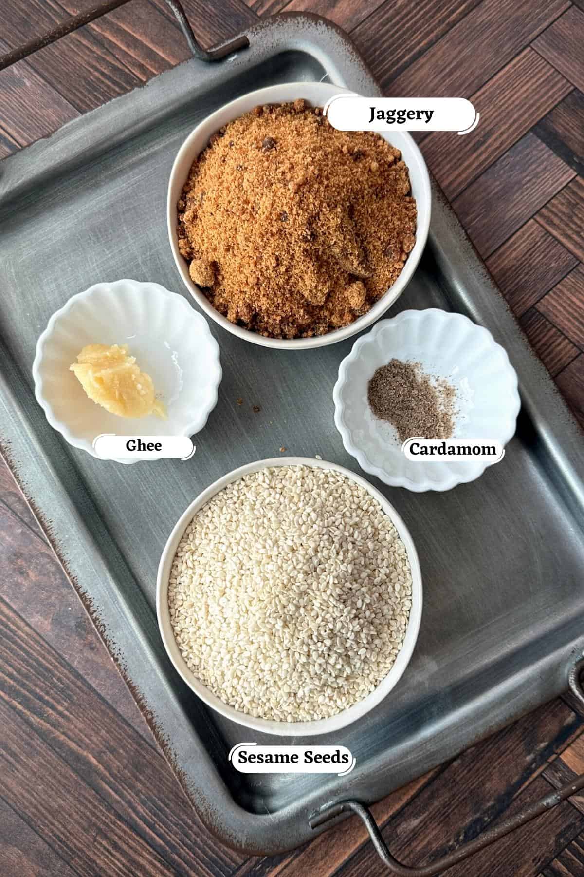 Sesame seeds, jaggery powder, ghee and cardamom powder on tray