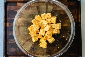 Marinating tofu cubes in a glass bowl