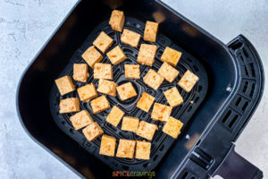 Uncooked tofu cubes in an air fryer basket