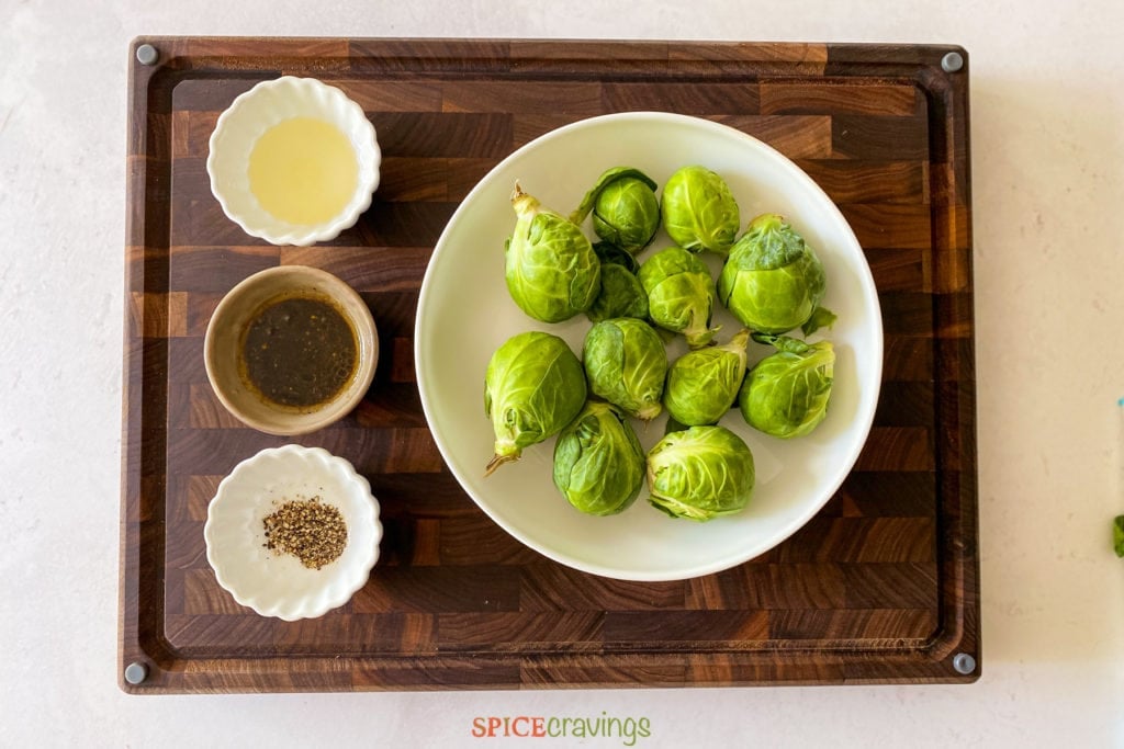 Bowl of brussel sprouts and seasoning bowls on a cutting board