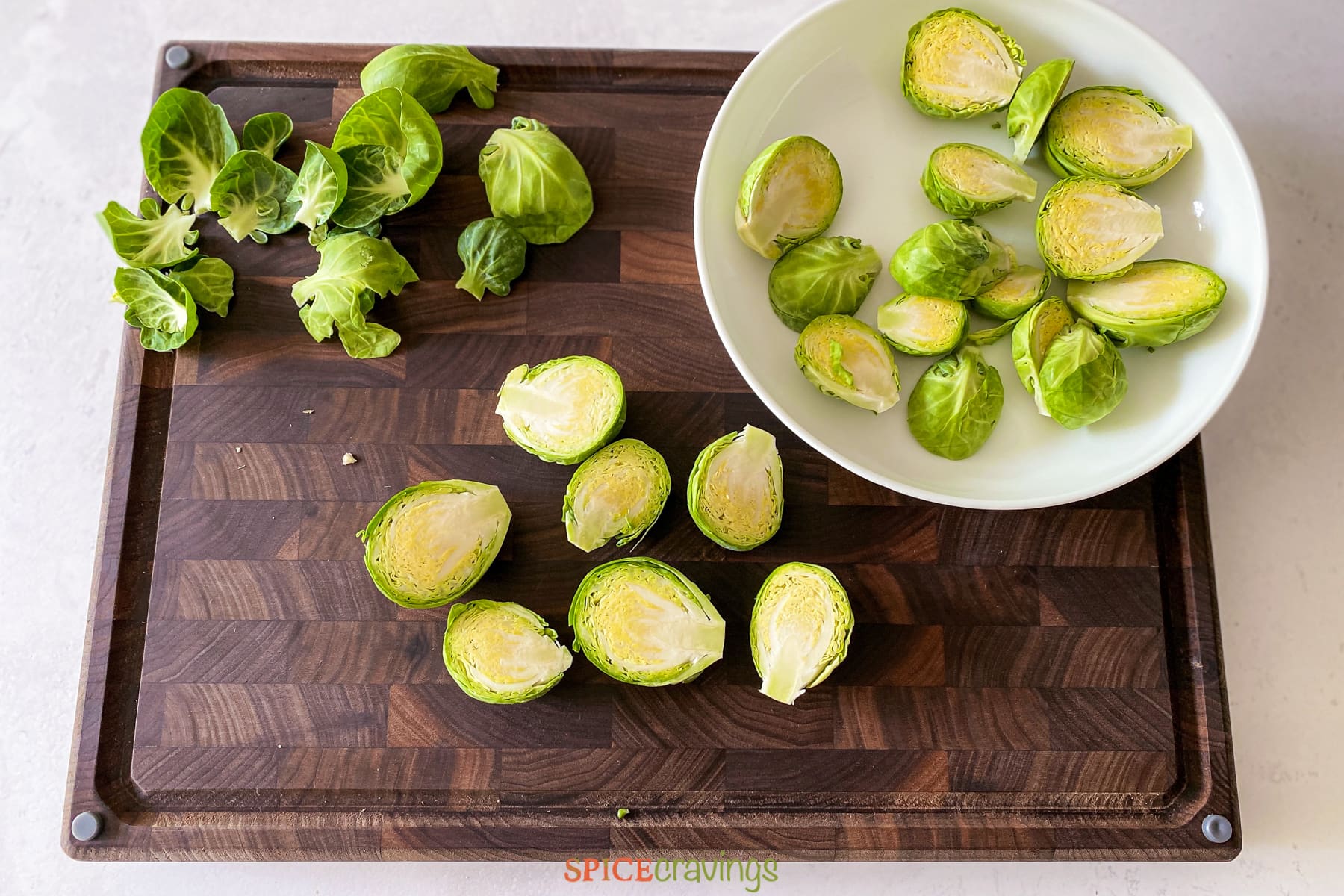 Halved brussel sprouts on cutting board and white bowl