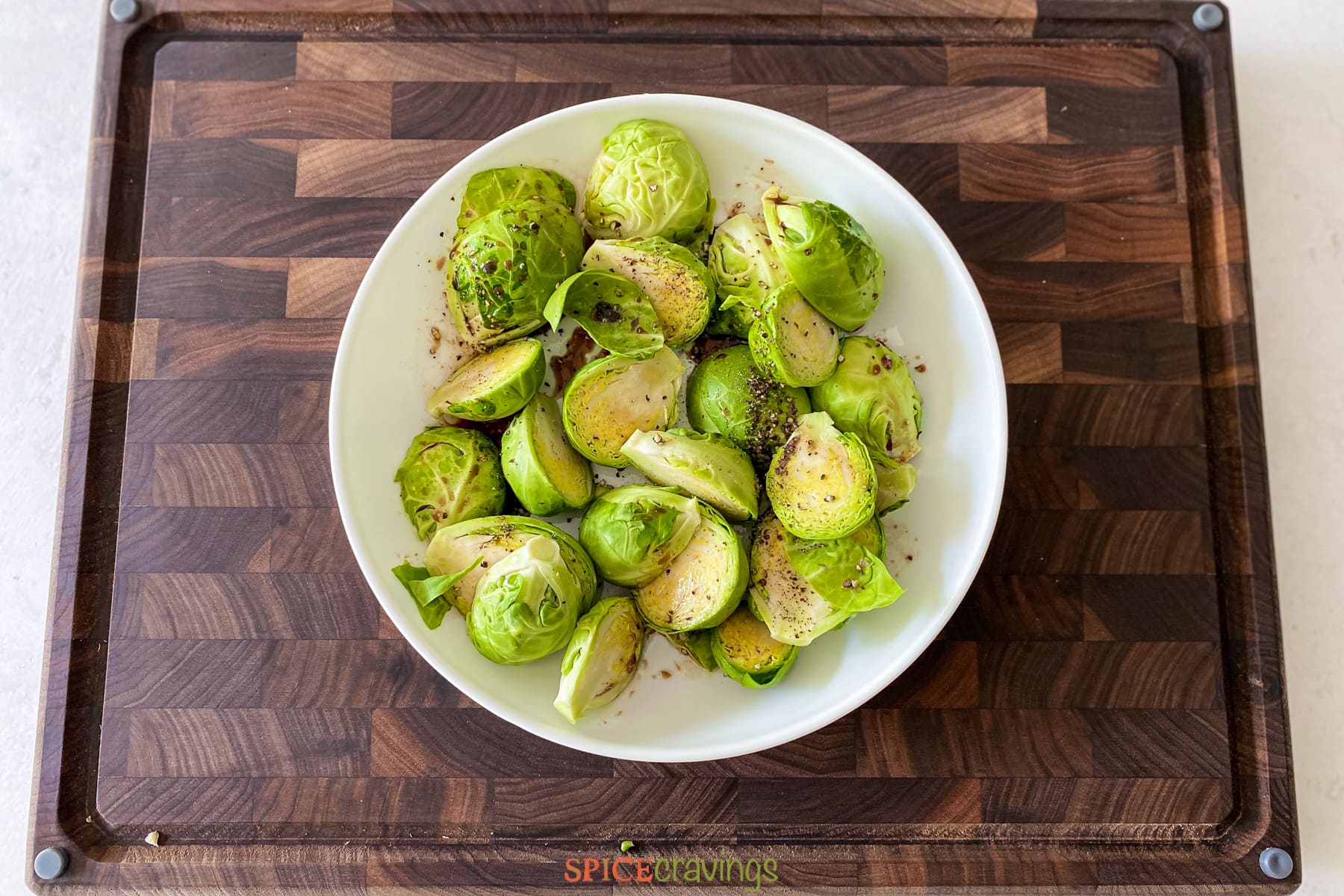Brussel sprouts with seasoning in white bowl on cutting bowl