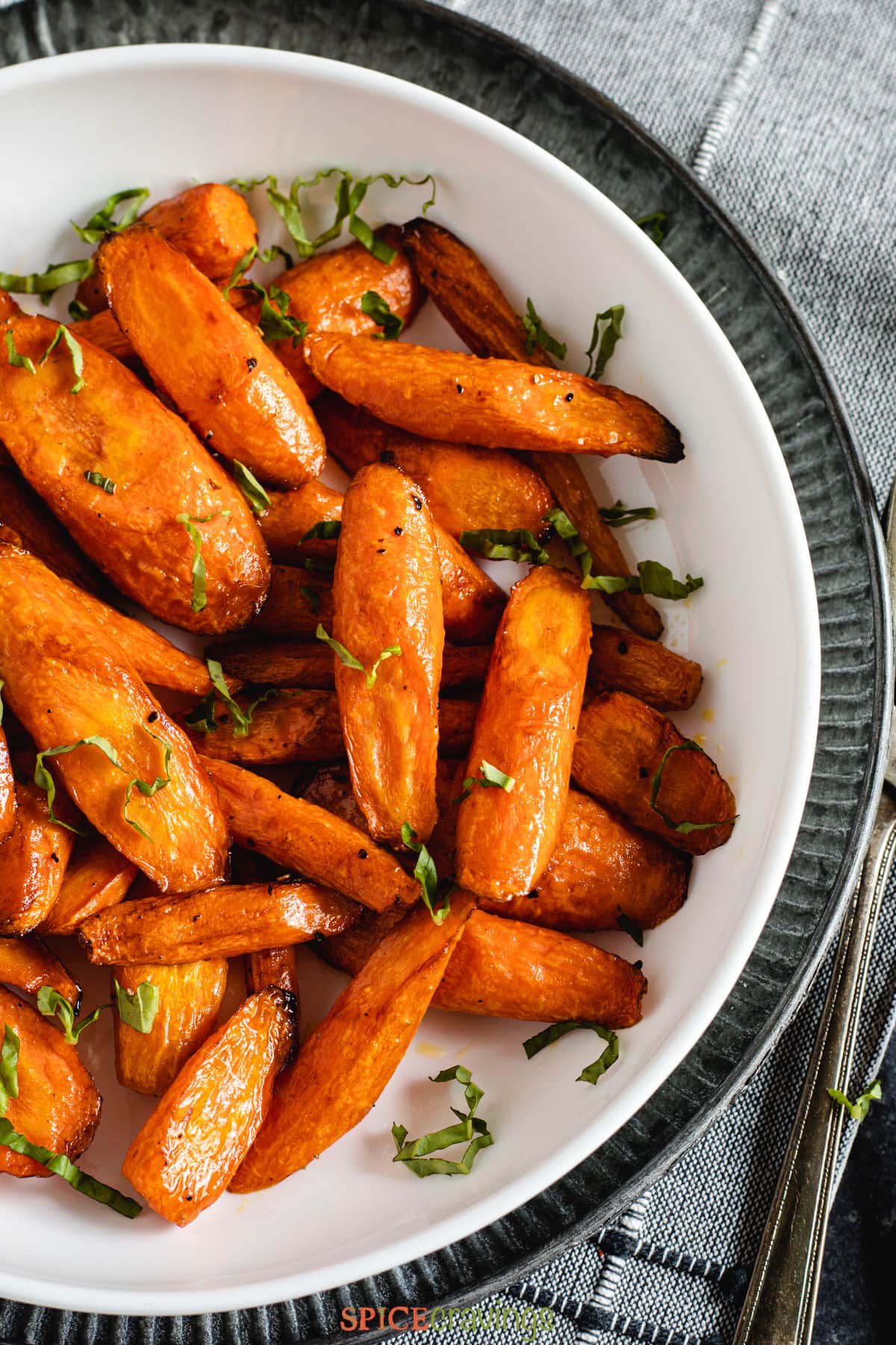 Roasted carrots in white bowl with basil strips on top