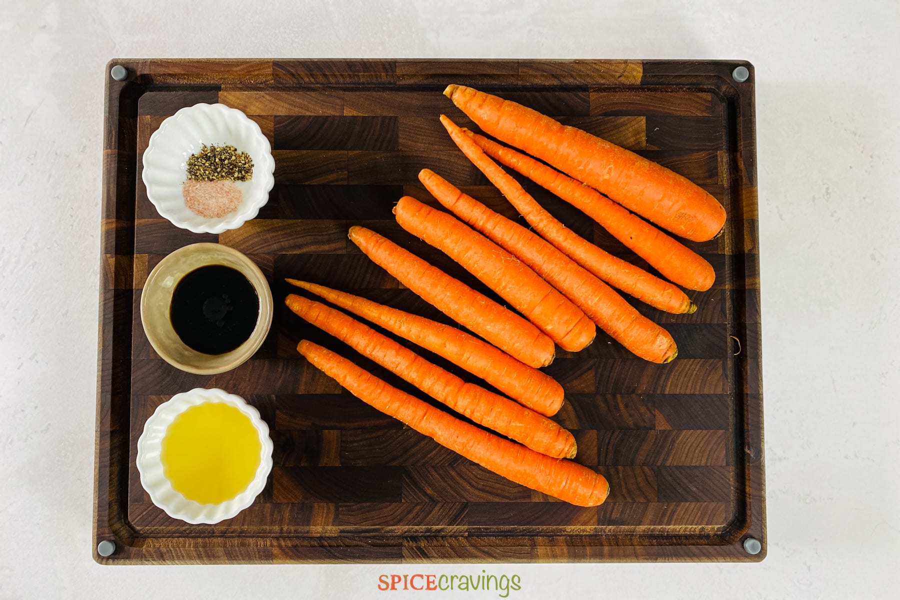 Carrots, vinegar, oil and spice bowl on wooden cutting board