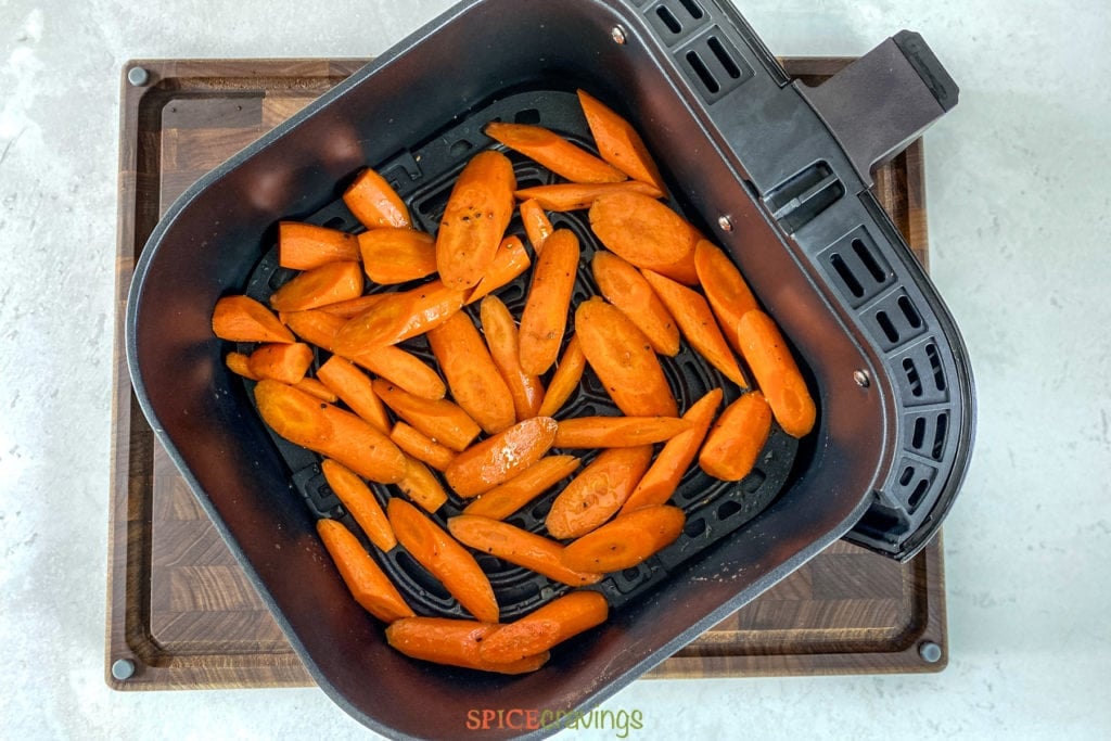 Seasoned carrot pieces in air fryer basket