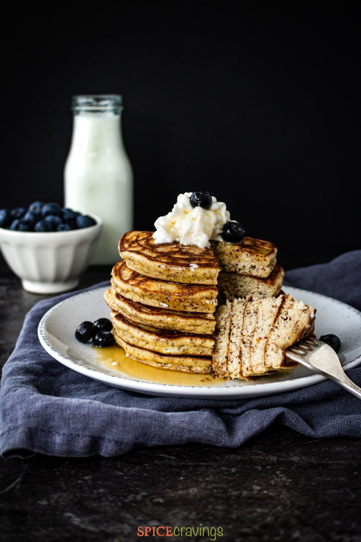 Stack of pancakes with blueberries and milk on the side