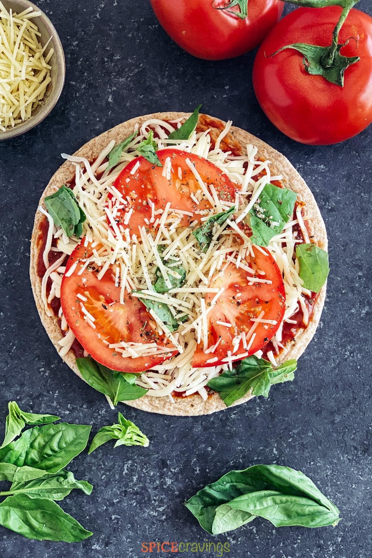 Assembled pizza with tomato, basil and cheese on flatbread